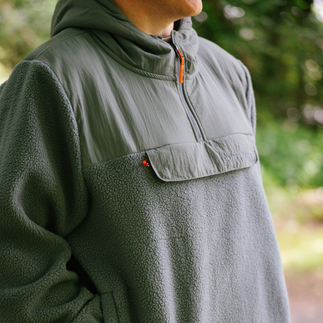 Person wearing a green Portwest fleece jacket with a hood in a natural setting